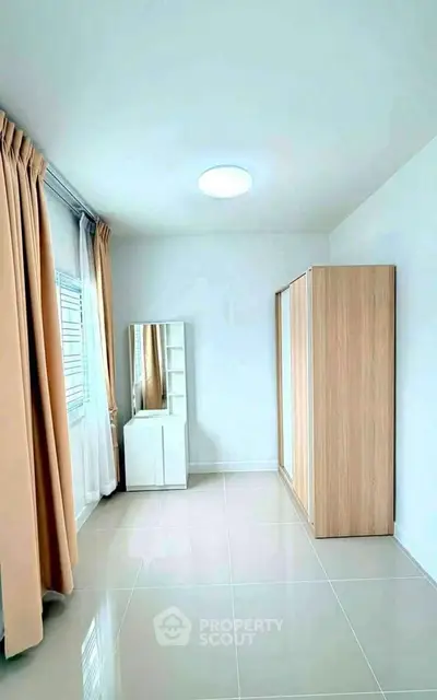 Spacious bedroom with natural light, modern wardrobe, and elegant curtains.