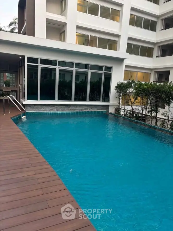 Luxurious apartment building with a pristine swimming pool and modern design.