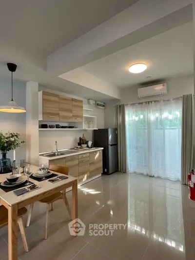 Modern kitchen with open layout, sleek cabinetry, and dining area in bright apartment.