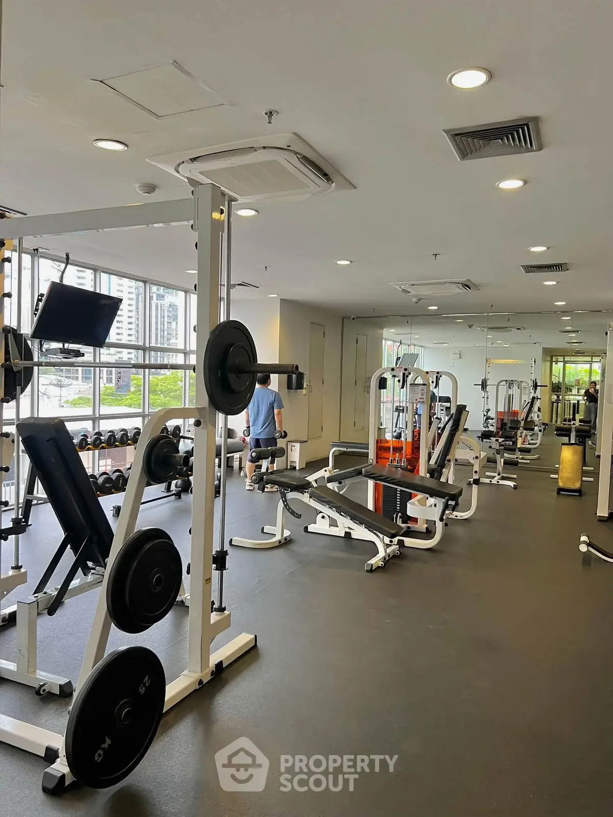 Spacious modern gym with state-of-the-art equipment and city view, perfect for fitness enthusiasts.