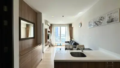 Modern living room with open kitchen and city view, featuring stylish decor and natural light.