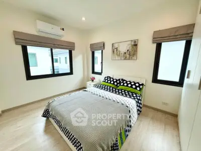 Modern bedroom with stylish decor and ample natural light, featuring a cozy bed and elegant furnishings.