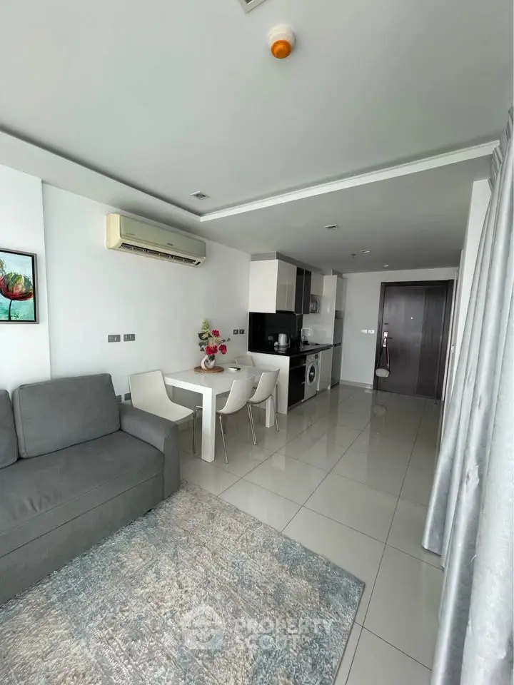 Modern open-plan living room with sleek kitchen and dining area in a stylish apartment.
