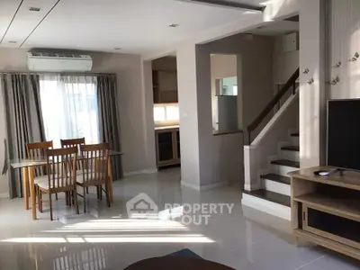 Spacious living room with dining area and staircase in modern home