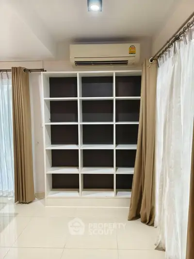 Spacious room with built-in shelving and air conditioning, ideal for modern living.