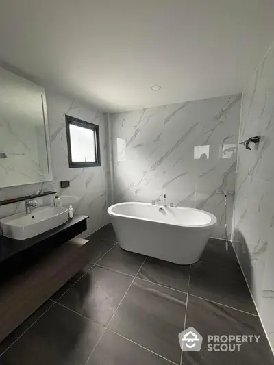 Modern bathroom with freestanding bathtub and elegant marble tiles