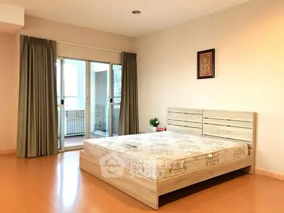 Spacious bedroom with wooden flooring and balcony access in modern apartment.