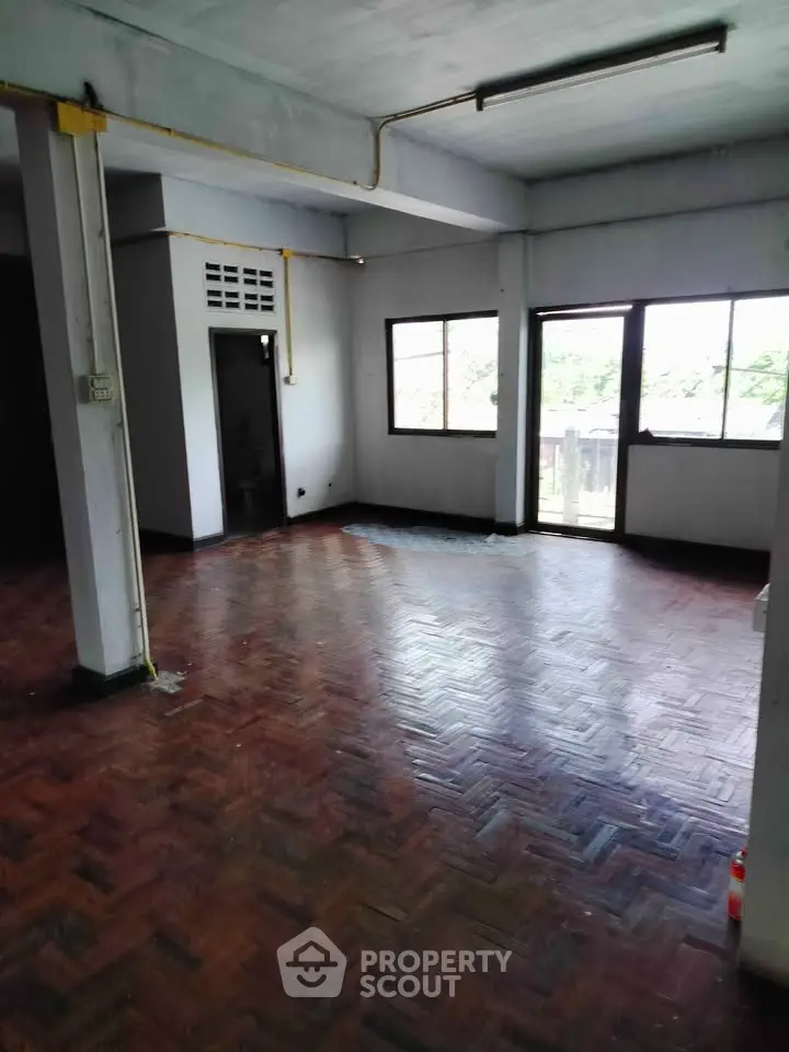 Spacious empty room with large windows and wooden flooring, ideal for customization.