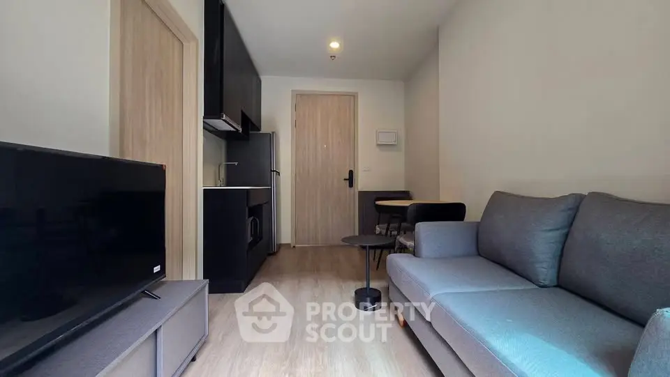 Modern living room with sleek furniture and compact kitchen in a cozy apartment.