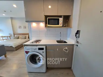 Compact modern kitchen with washing machine and microwave in cozy apartment