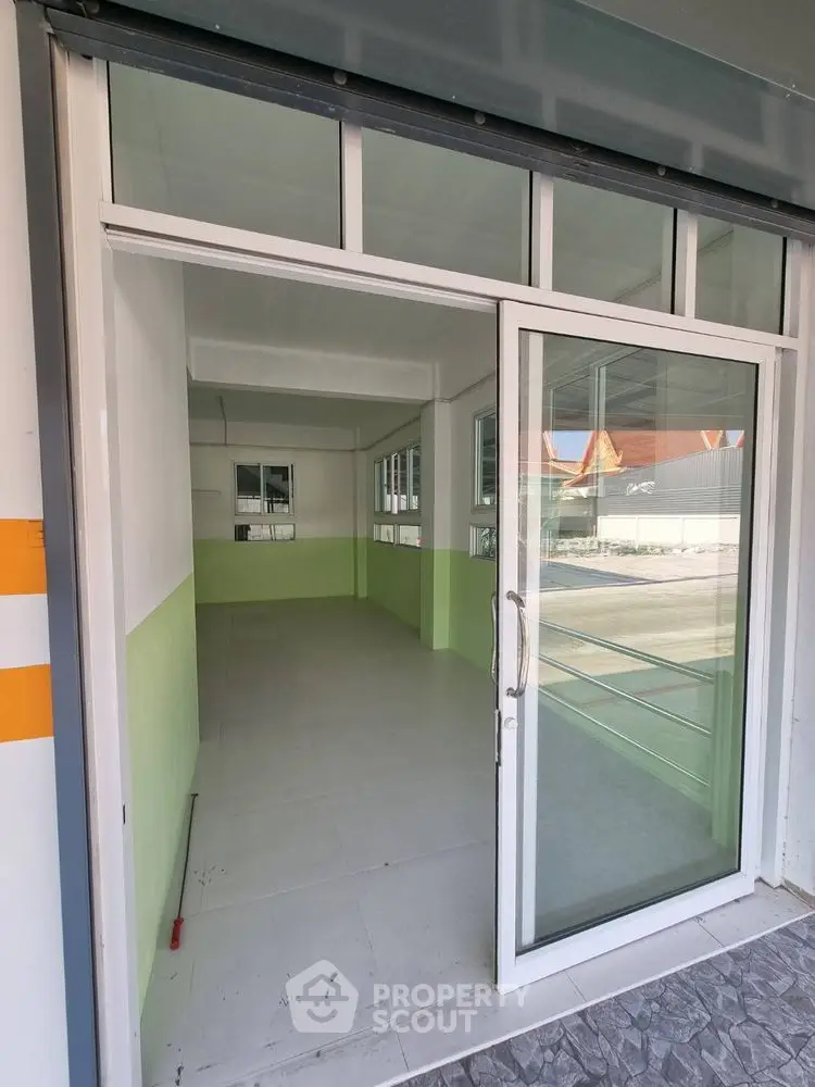 Spacious commercial space with glass door entrance and tiled flooring, ideal for retail or office use.