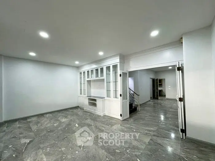 Spacious living room with elegant marble flooring and built-in cabinetry