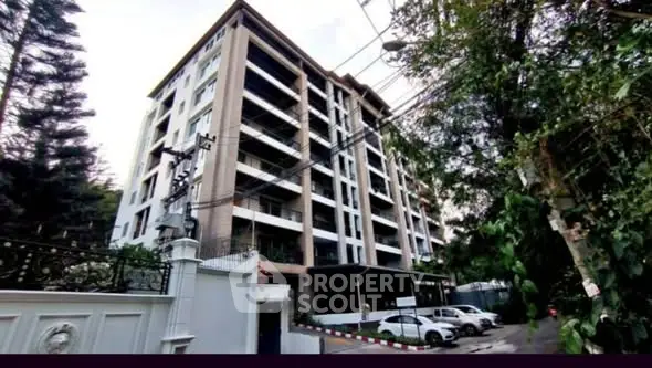Modern multi-story residential building with lush greenery and ample parking space.