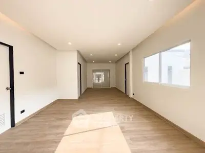 Spacious modern living room with wooden flooring and ample natural light.