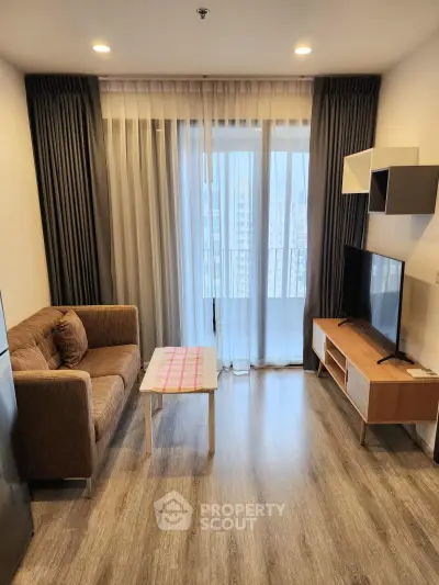 Modern living room with cozy sofa, TV, and large window offering city view in stylish apartment.