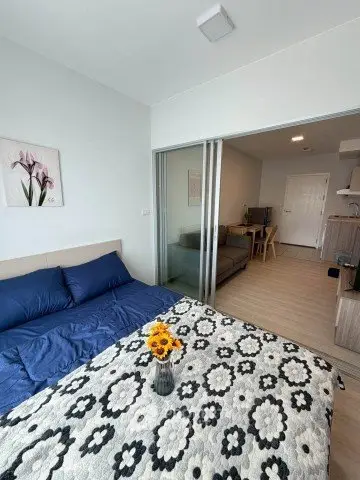 Modern studio apartment with cozy bedroom and stylish living area, featuring sliding glass doors and elegant decor.