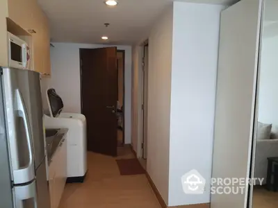 Modern apartment hallway with kitchen and washing machine, featuring sleek appliances and wooden flooring.