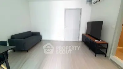 Modern living room with sleek furniture and minimalist design, featuring a comfortable sofa and large TV.