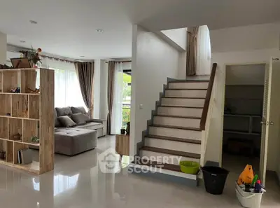 Spacious modern living room with staircase and large windows, perfect for family gatherings.