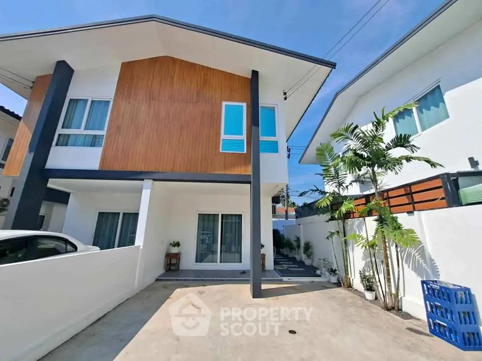 Modern two-story house with wooden facade and spacious driveway in sunny neighborhood.