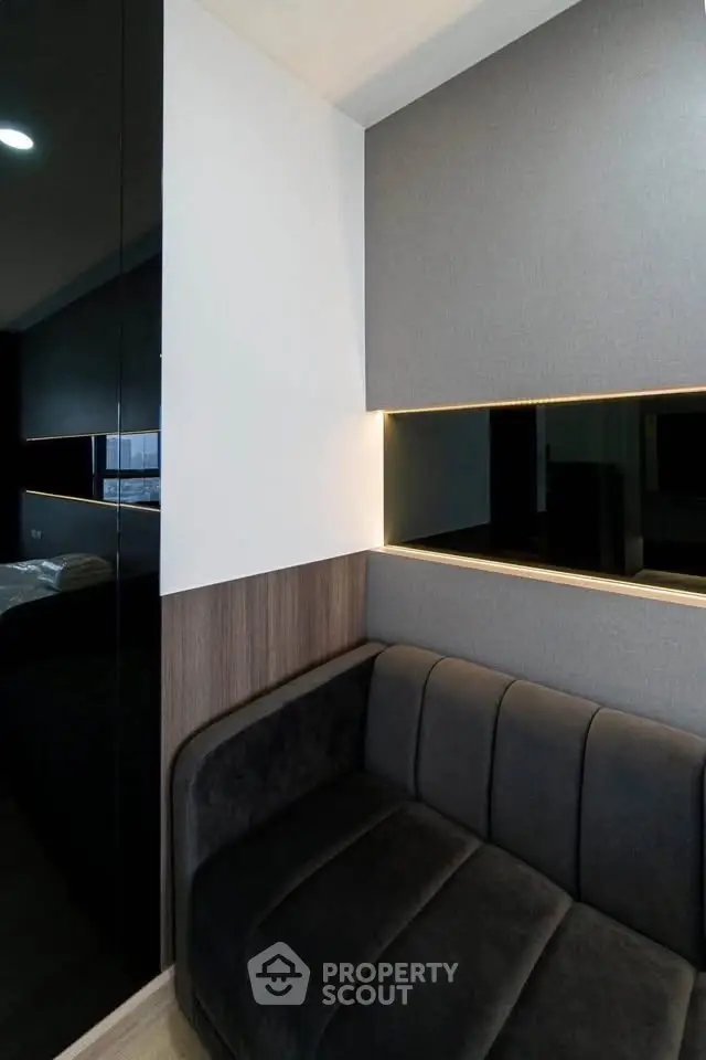 Modern living room with sleek black sofa and stylish wall paneling