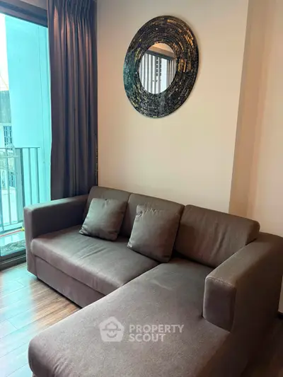 Modern living room with stylish sofa and decorative mirror, featuring a cozy ambiance and natural light.