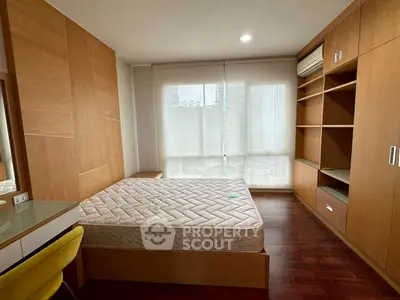 Spacious bedroom with built-in wooden wardrobe and large window for natural light.