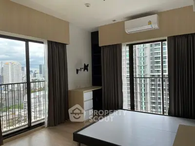 Modern bedroom with large windows offering stunning city views and ample natural light.