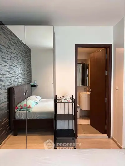 Modern bedroom with mirrored wardrobe and ensuite bathroom, featuring stylish decor and cozy ambiance.