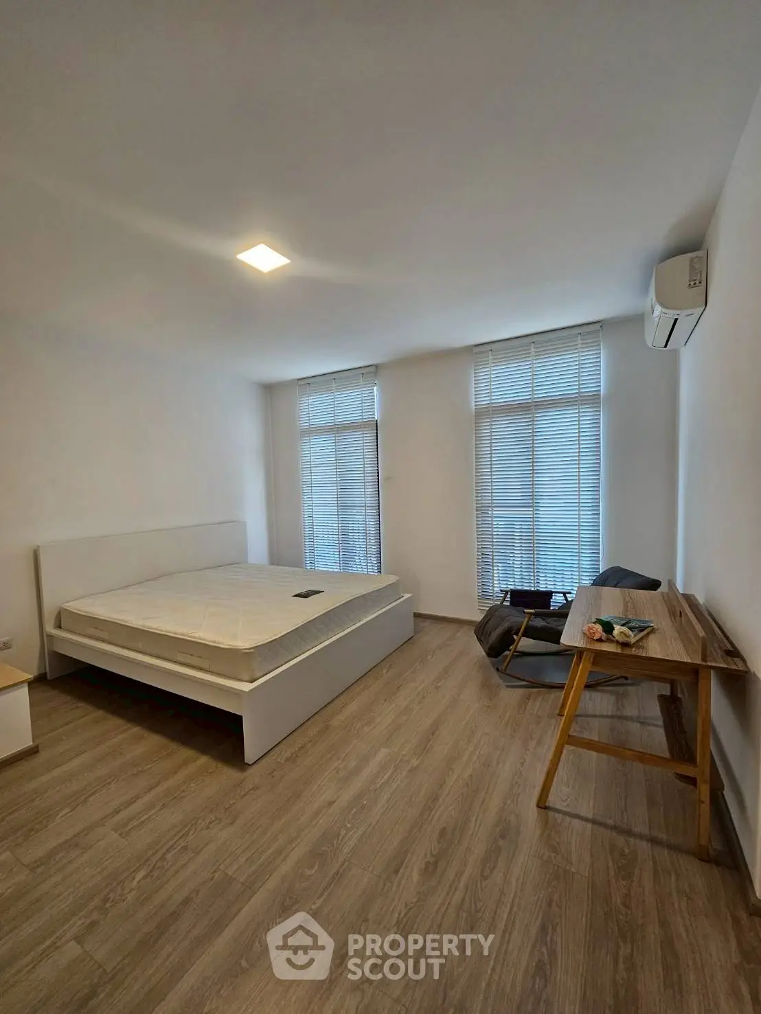 Spacious bedroom with modern decor and natural light, featuring a comfortable bed and stylish desk.