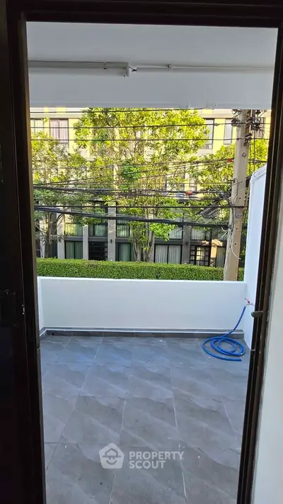 Spacious balcony with modern tiles and lush green view, perfect for relaxation.