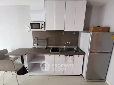 Modern compact kitchen with sleek white cabinets and stainless steel appliances.