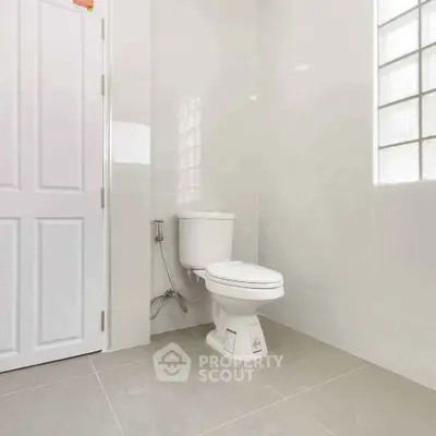 Modern bathroom with sleek white tiles and contemporary toilet design.