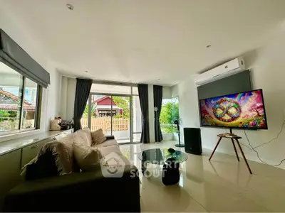 Spacious living room with modern decor and large windows offering natural light and garden view.