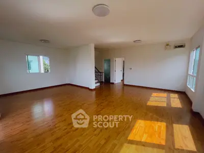 Spacious empty living room with wooden flooring and ample natural light