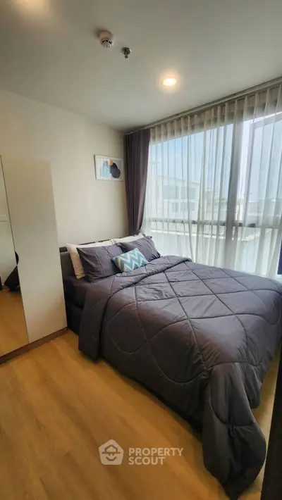 Modern bedroom with large windows and stylish decor in a contemporary apartment.