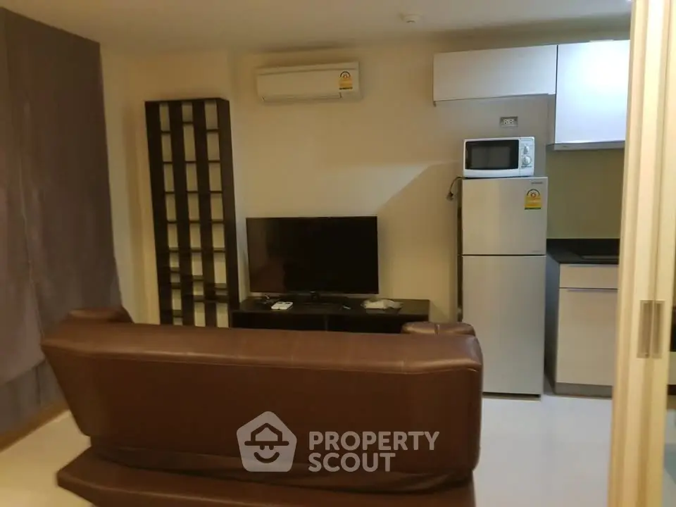 Cozy living room with modern appliances and sleek furniture in a compact apartment setting.