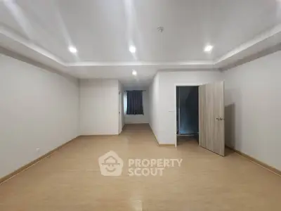 Spacious empty room with wooden flooring and recessed lighting, ideal for customization.