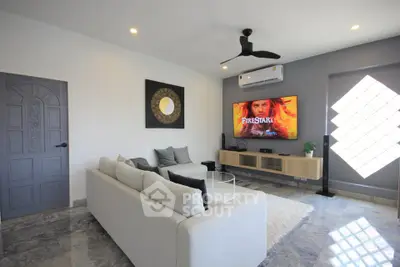 Modern living room with sleek design, featuring a large TV and stylish furniture.