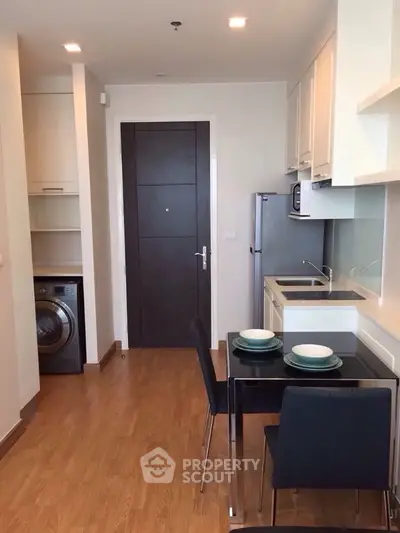 Modern kitchen with dining area and washing machine in compact apartment