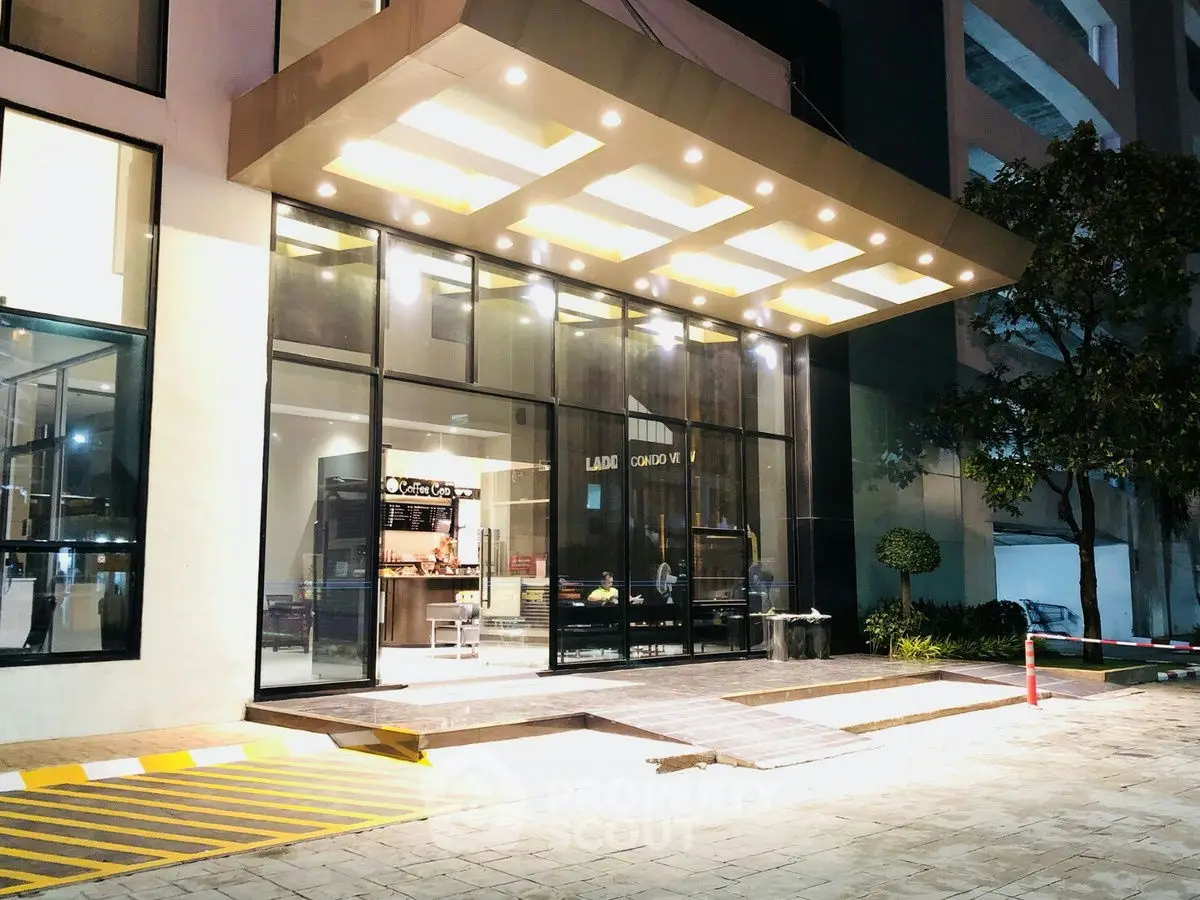 Modern building entrance with illuminated canopy and glass facade at night.