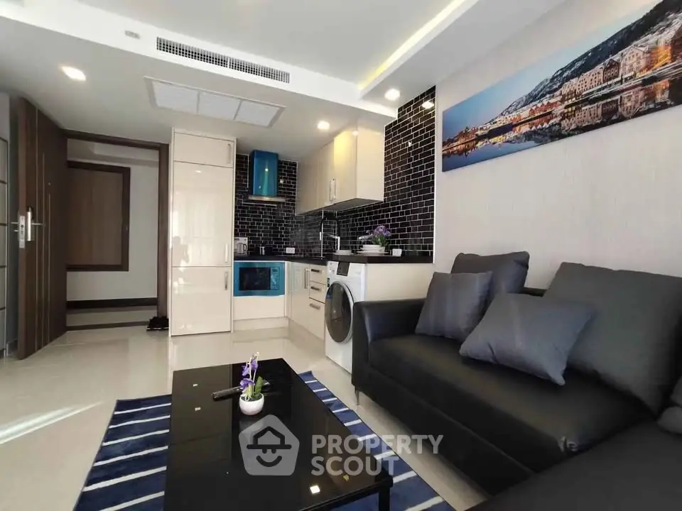 Modern living room with sleek black sofa and stylish kitchen area