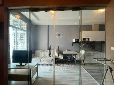 Modern living room with glass partition, cozy sofa, and sleek kitchen area.