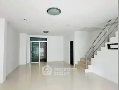 Spacious modern living room with sleek staircase and polished floors in a minimalist design.