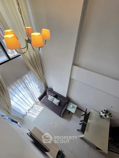 Modern loft-style living room with high ceilings and elegant chandelier