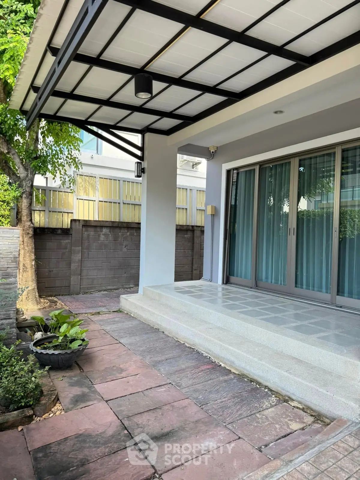 Charming modern home entrance with covered patio and lush greenery