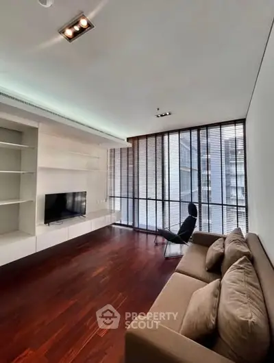 Modern living room with sleek design, hardwood floors, and large windows offering natural light.