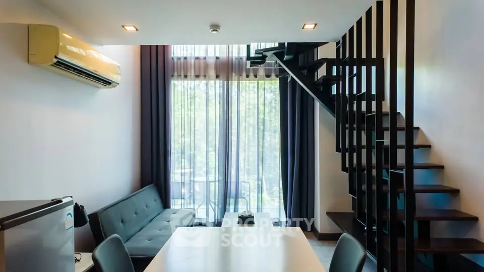 Modern duplex living room with stylish staircase and large windows