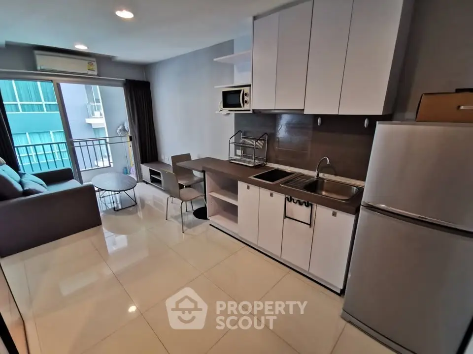 Modern open-layout kitchen with sleek cabinets and cozy living area in a stylish apartment.