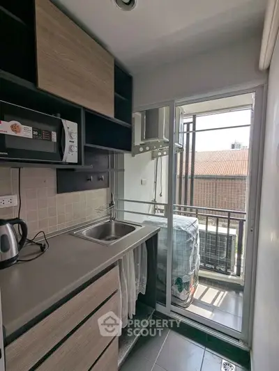 Compact kitchen with modern appliances and balcony access in urban apartment